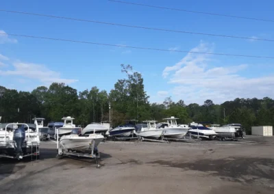 Several boats parked in a lot at Matthews Boat and RV Storage, showcasing a variety of sizes and styles.